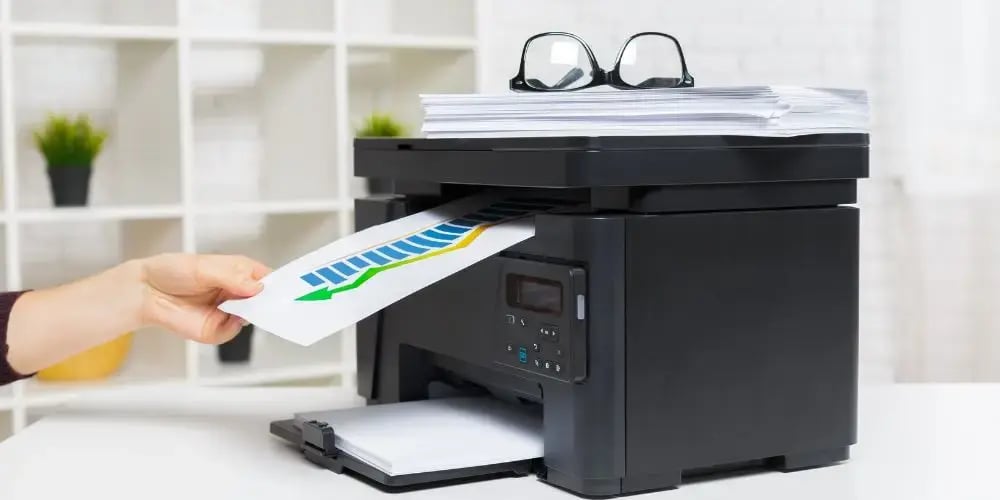 Person standing next to a printer with a colorful print job